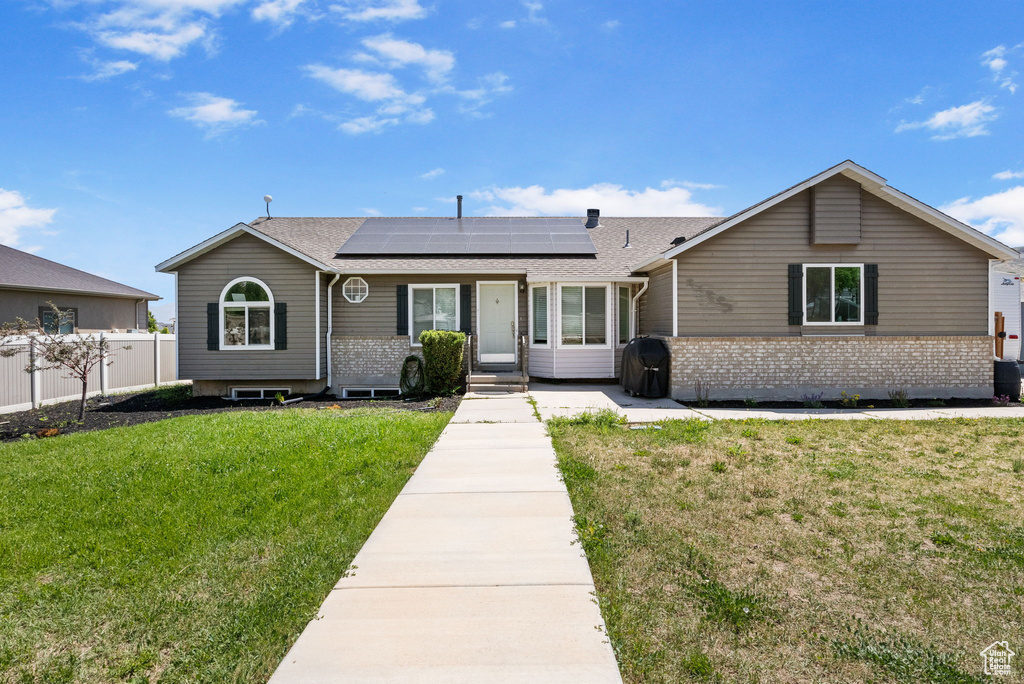 Ranch-style house with solar panels, brick siding, and a shingled roof