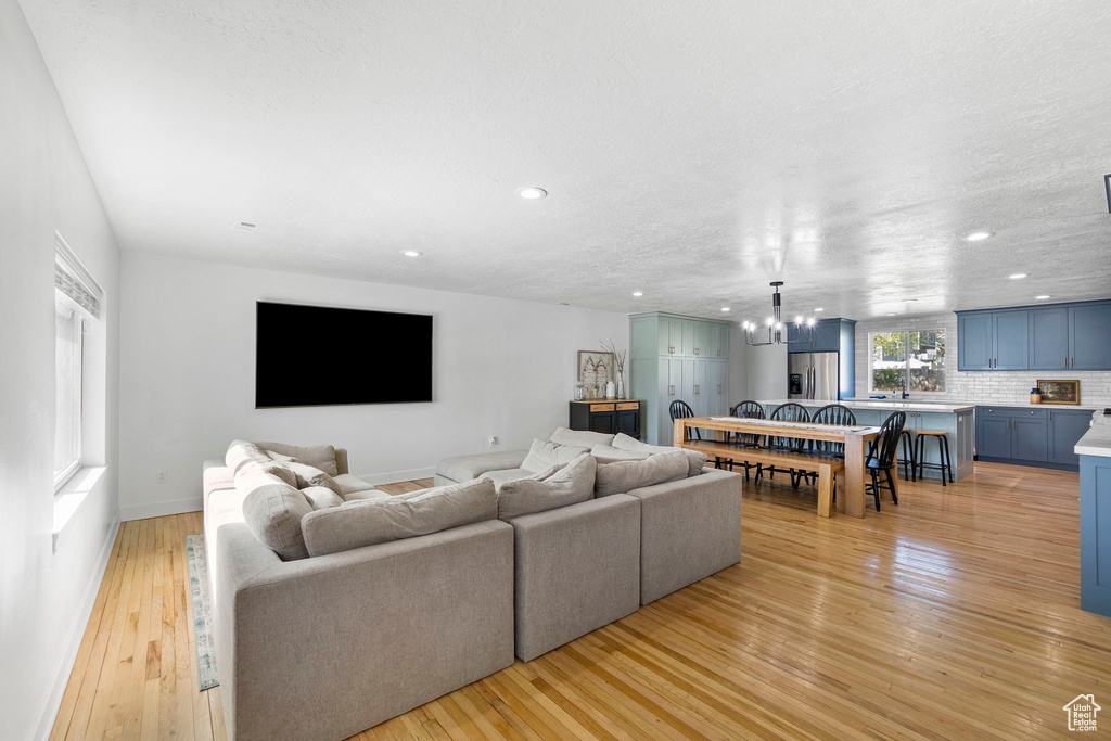Living area with a chandelier, light wood finished floors, recessed lighting, and baseboards