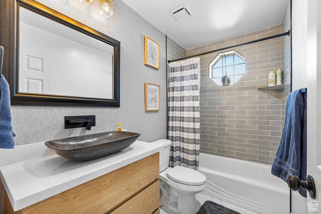 Bathroom featuring toilet, vanity, and shower / tub combo