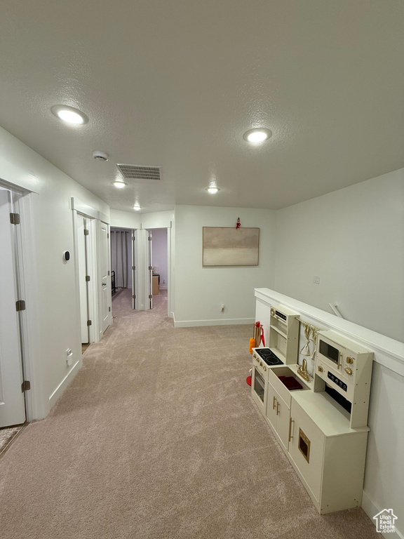 Corridor featuring a textured ceiling, light carpet, baseboards, recessed lighting, and washer / dryer