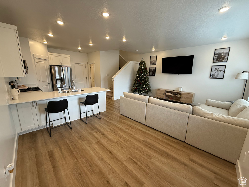 Living room with stairway, recessed lighting, and light wood-style floors