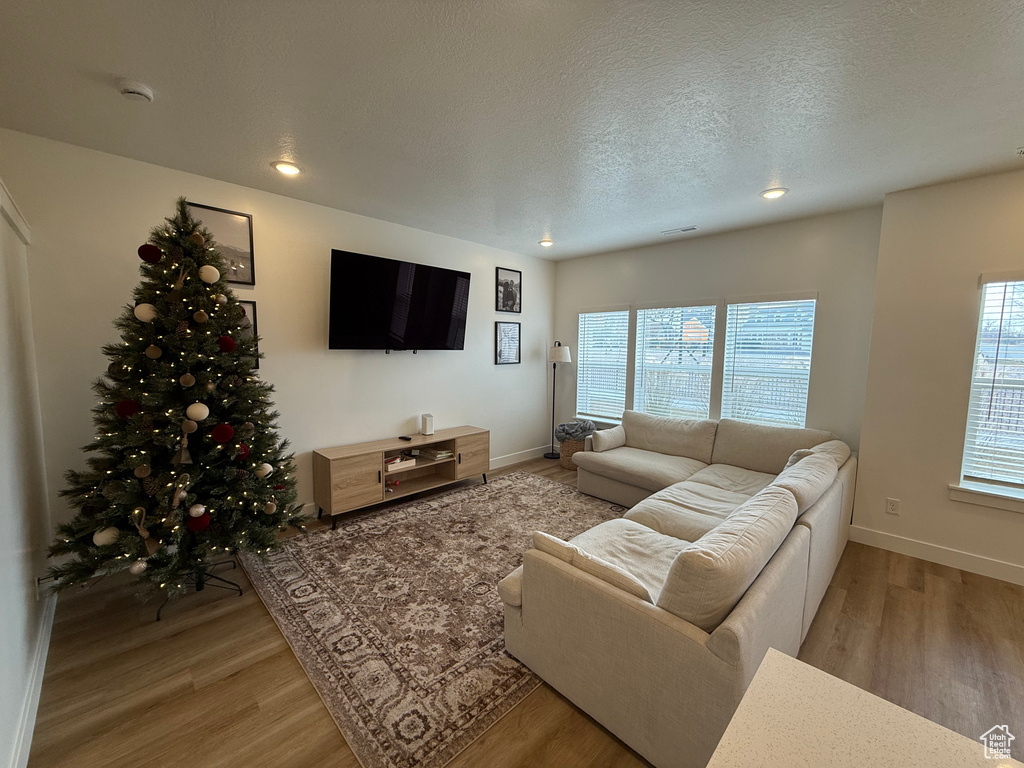 Living area with light wood-style floors, recessed lighting, baseboards, and a textured ceiling