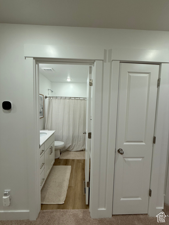 Full bath featuring vanity, toilet, wood finished floors, and curtained shower