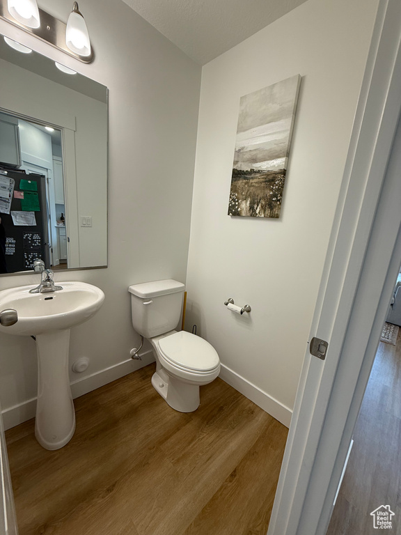 Half bath with wood finished floors, toilet, and baseboards