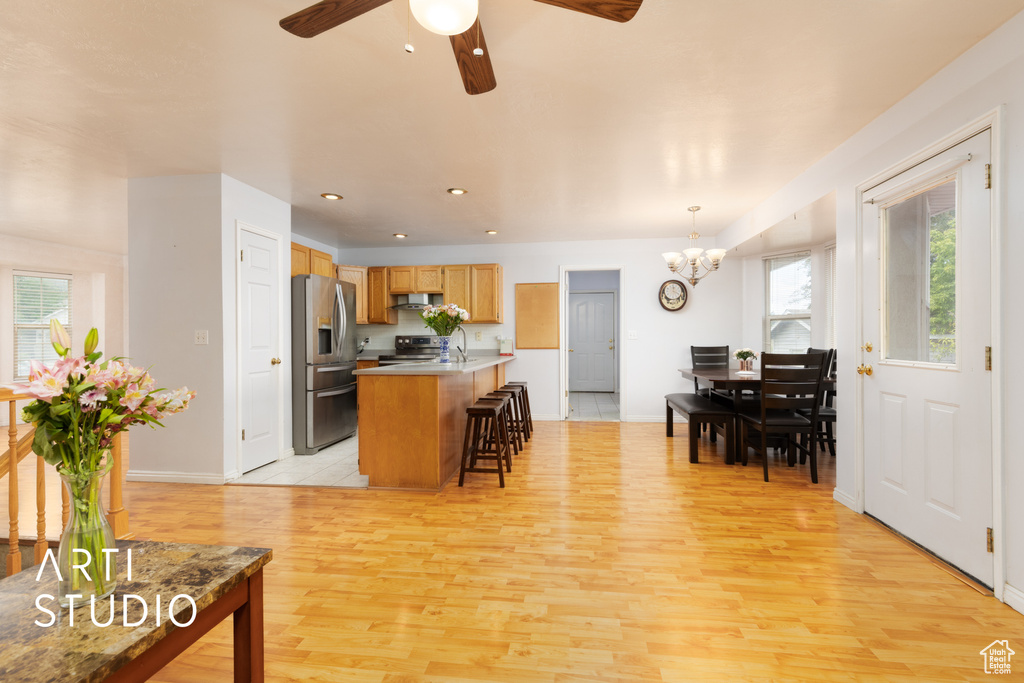 Kitchen with appliances with stainless steel finishes, plenty of natural light, a kitchen bar, light wood-style floors, and recessed lighting