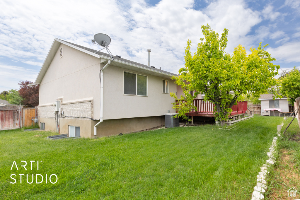 Rear view of property with stucco siding, a wooden deck, and central AC