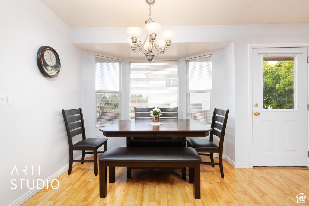 Dining area with a chandelier, light wood-style flooring, and baseboards