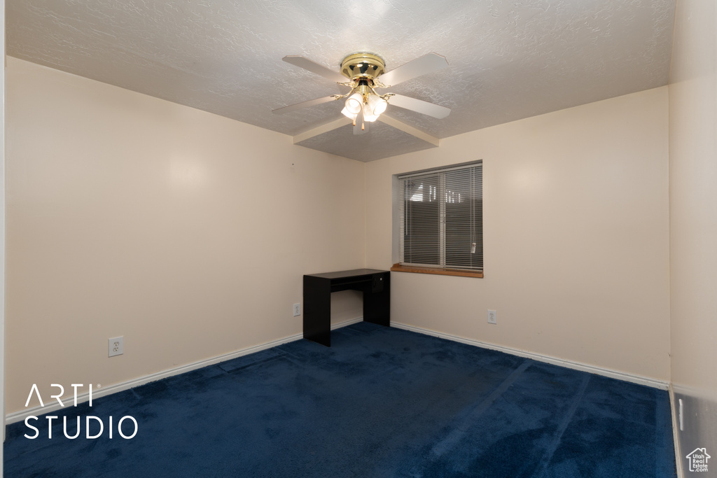 Empty room with a ceiling fan, a textured ceiling, dark colored carpet, and baseboards