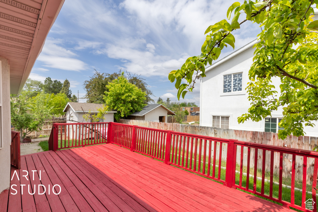 Wooden deck featuring a fenced backyard, an outdoor structure, and a storage shed