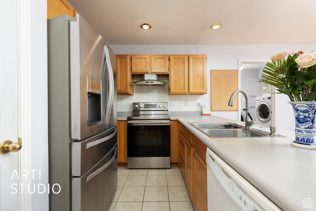 Kitchen with appliances with stainless steel finishes, ventilation hood, a sink, light countertops, and backsplash