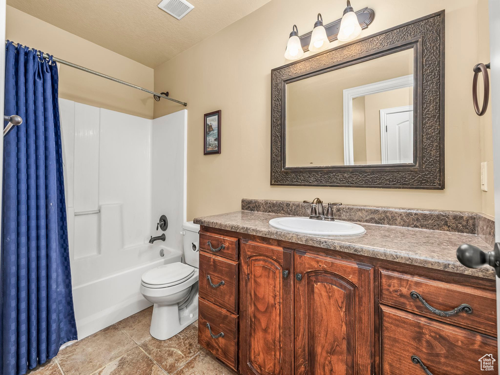 Full bath with toilet, vanity, shower / bathtub combination with curtain, and tile patterned floors