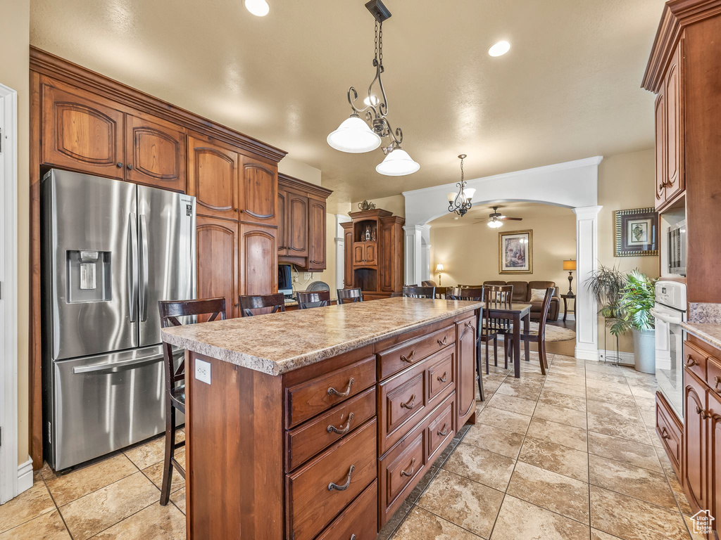 Kitchen with stainless steel fridge with ice dispenser, a center island, decorative columns, oven, and a breakfast bar