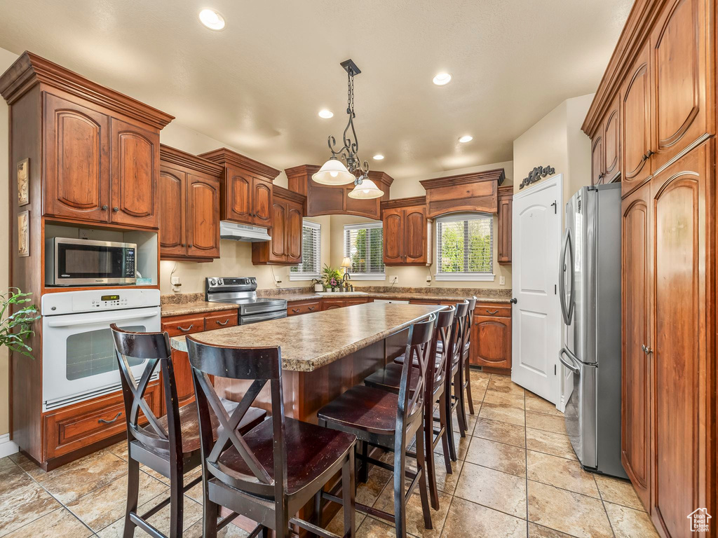Kitchen featuring appliances with stainless steel finishes, recessed lighting, a center island, a breakfast bar area, and under cabinet range hood