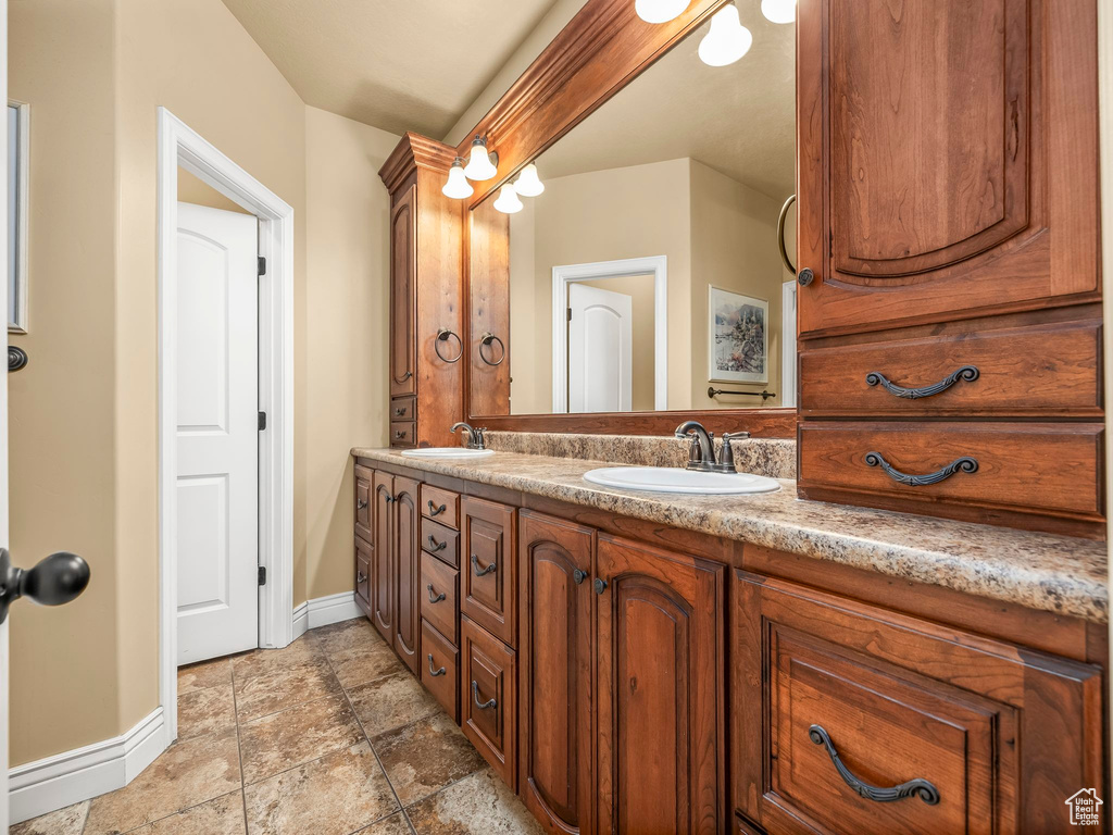 Bathroom with baseboards, stone finish floors, and double vanity