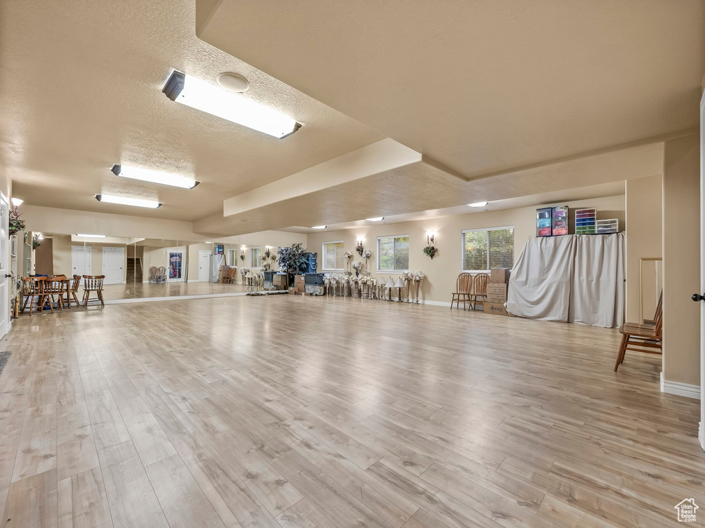 Exercise room with wood finished floors, baseboards, and a textured ceiling