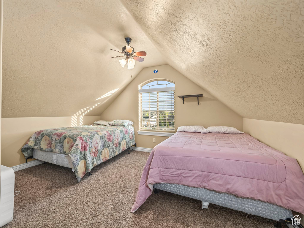 Carpeted bedroom featuring a textured ceiling, lofted ceiling, ceiling fan, and baseboards