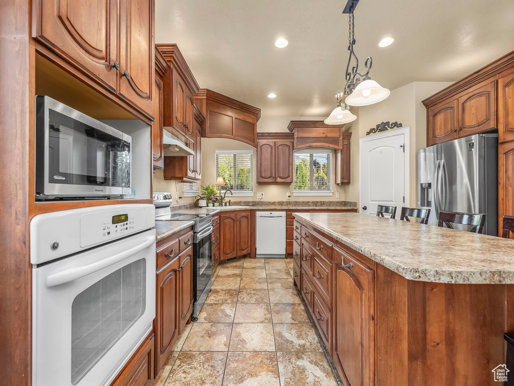 Kitchen featuring stainless steel appliances, a center island, light countertops, recessed lighting, and decorative light fixtures