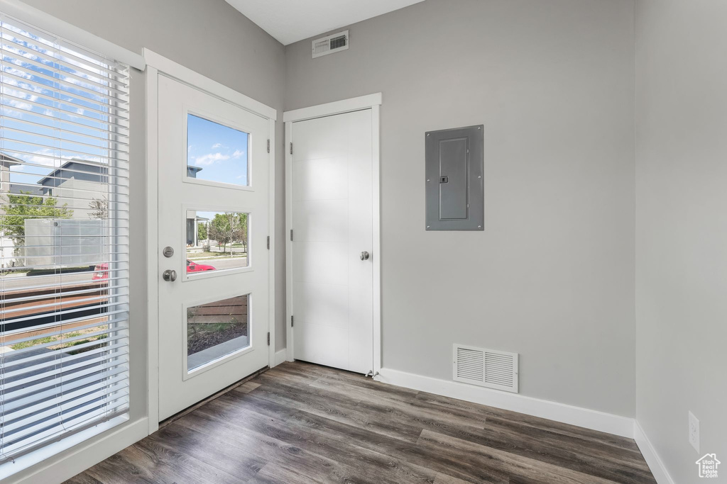 Doorway to outside featuring electric panel, dark wood-style flooring, and baseboards