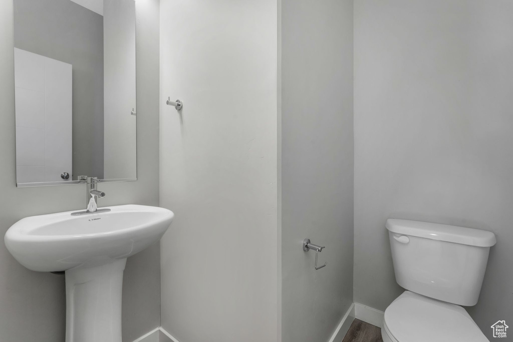 Half bath featuring toilet, baseboards, and wood finished floors