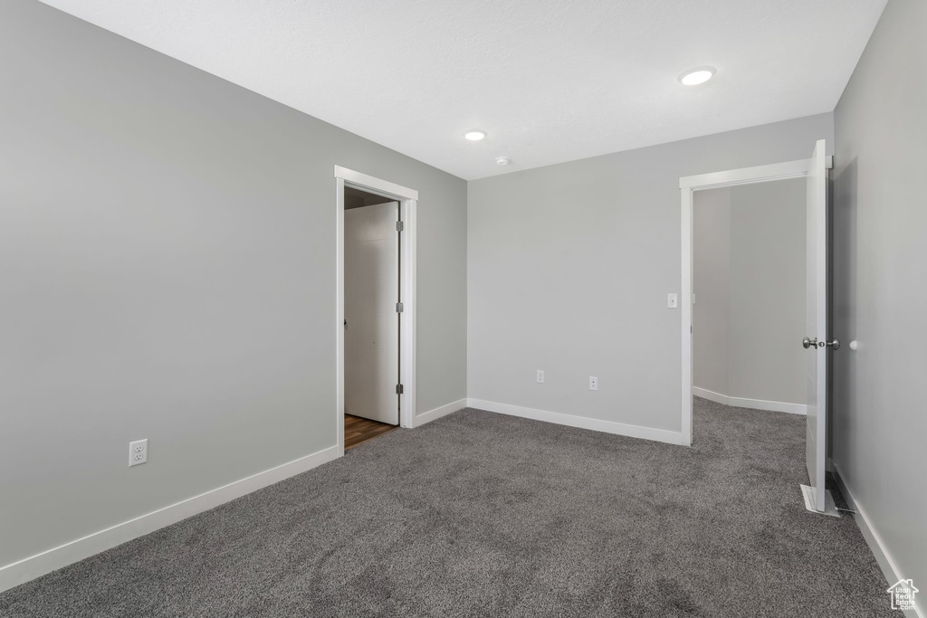 Unfurnished bedroom with dark colored carpet, baseboards, and recessed lighting