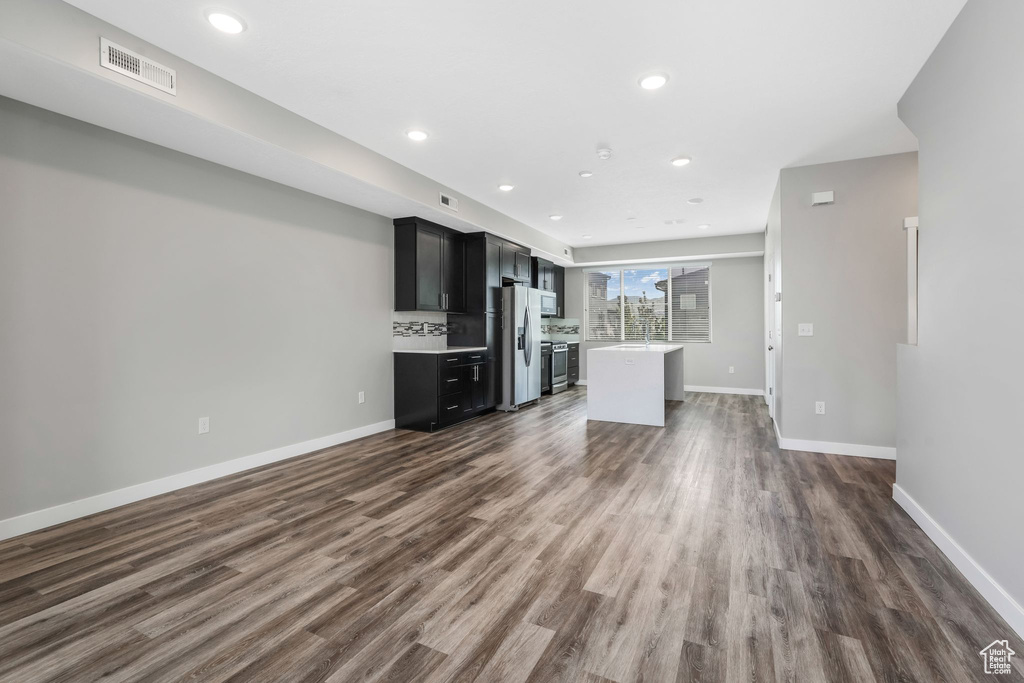 Unfurnished living room with dark wood-type flooring, baseboards, and recessed lighting