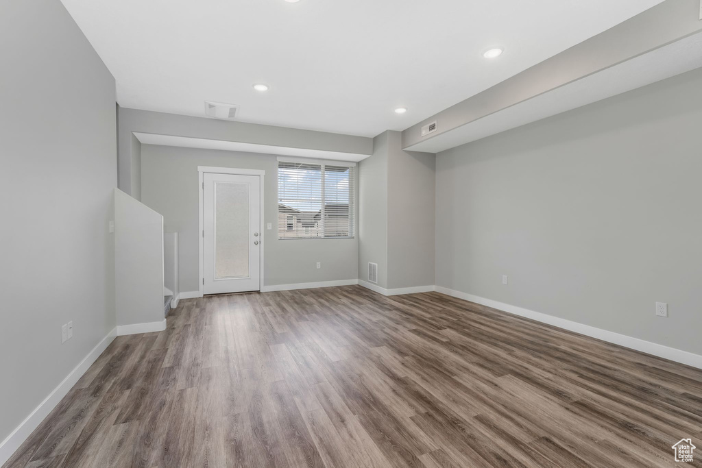Unfurnished living room with wood finished floors, baseboards, and recessed lighting