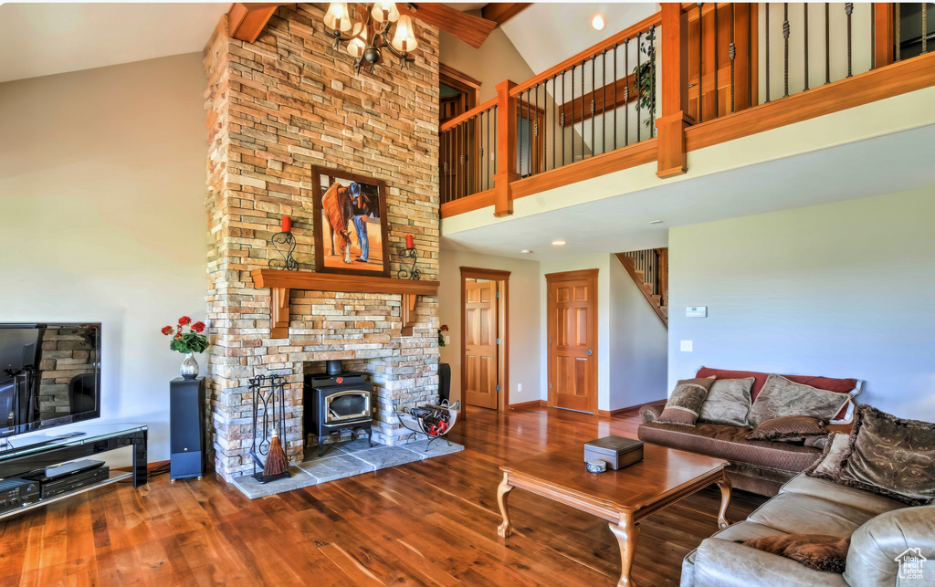 Living area with wood finished floors, high vaulted ceiling, baseboards, a wood stove, and stairs