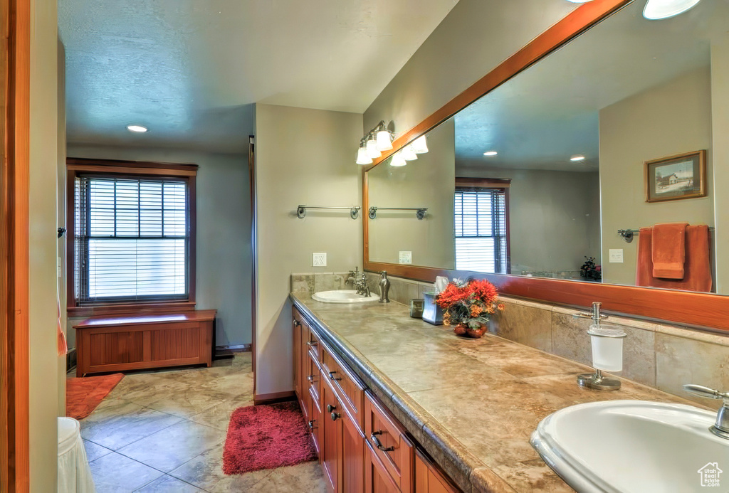 Bathroom with recessed lighting, double vanity, baseboards, and a sink