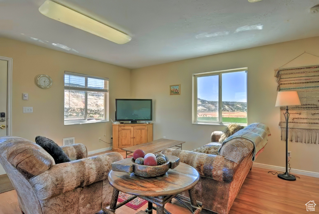 Living room with light wood finished floors, baseboards, and visible vents