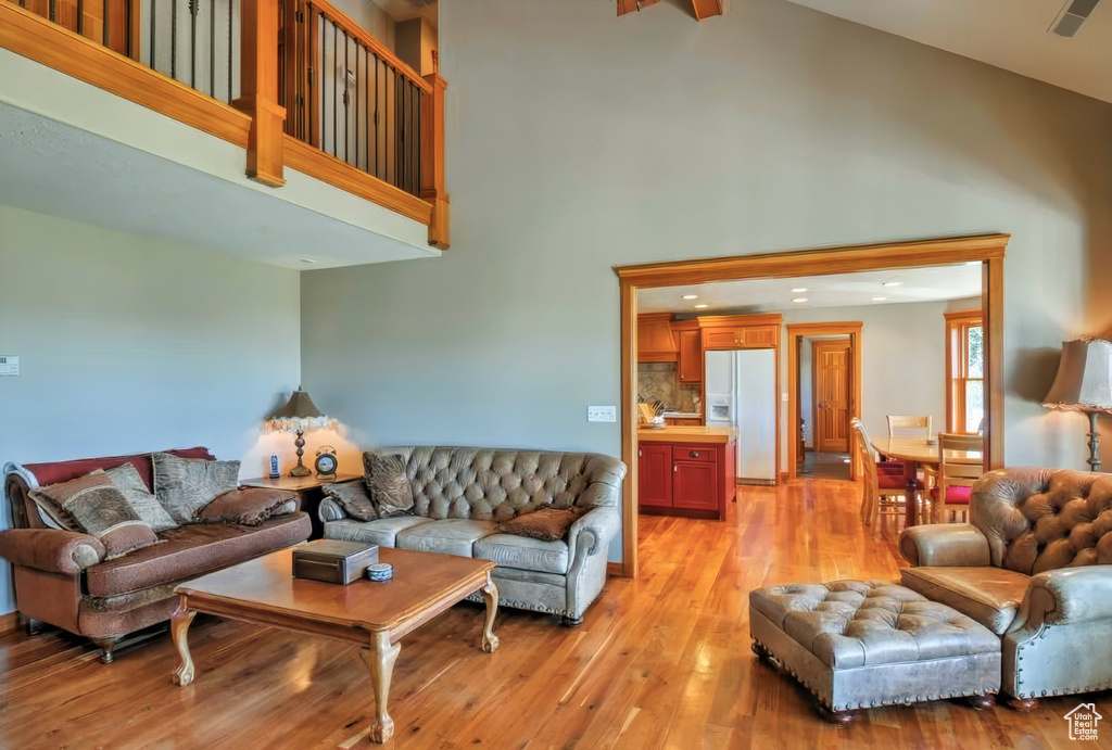 Living room featuring light wood finished floors, high vaulted ceiling, and recessed lighting