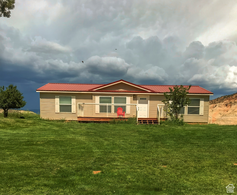 Rear view of property featuring a lawn, metal roof, and a wooden deck