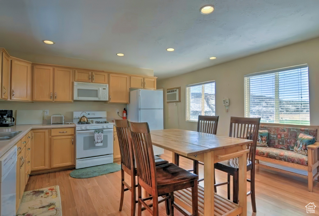 Kitchen featuring white appliances, light wood finished floors, light countertops, and light brown cabinetry