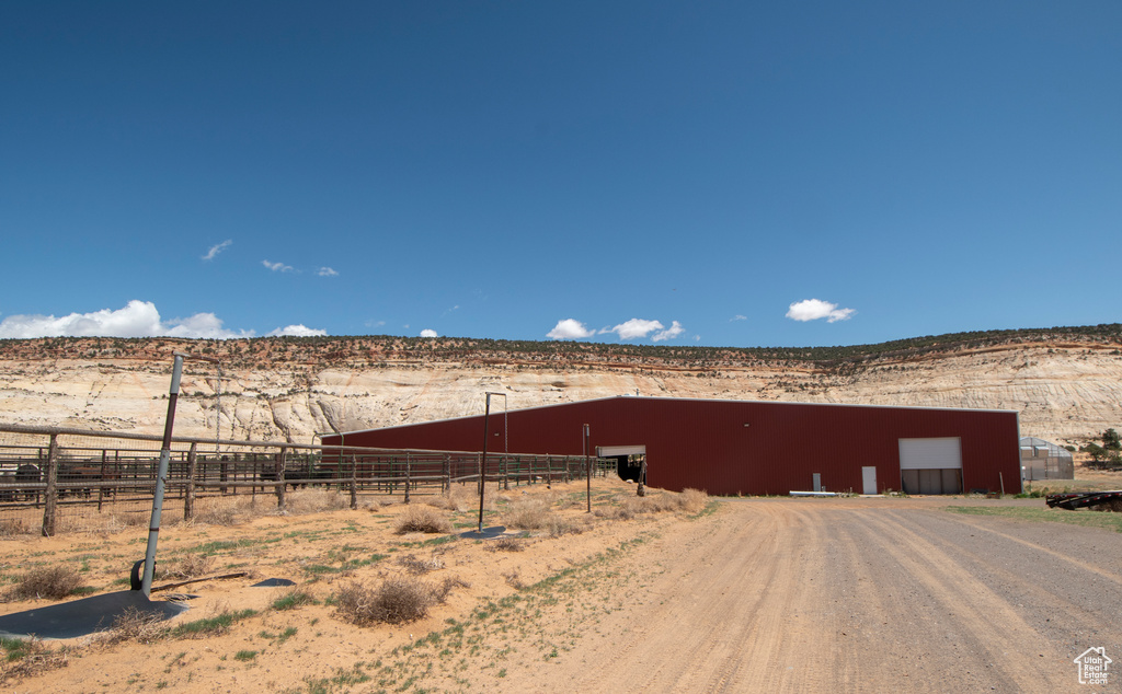 View of pole building featuring fence, a view of rural / pastoral area, a mountain view, and dirt driveway