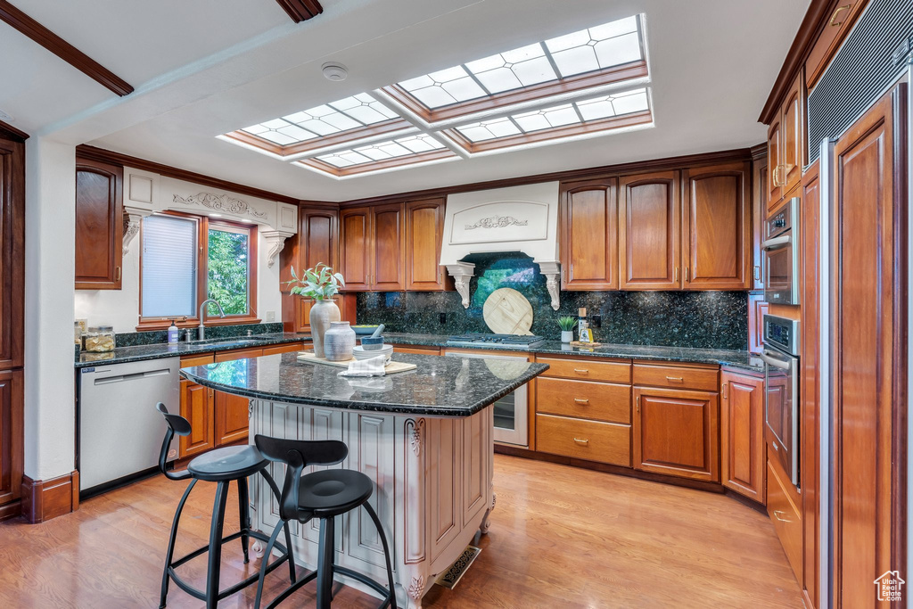 Kitchen with stainless steel appliances, light wood-type flooring, a kitchen bar, and a kitchen island