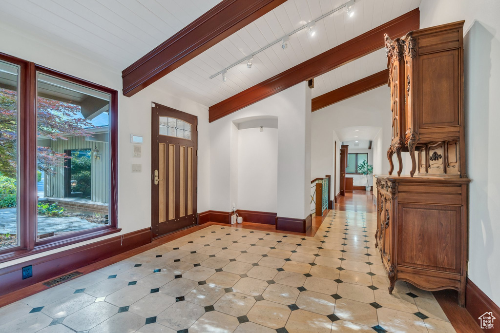 Entrance foyer with arched walkways, baseboards, and track lighting