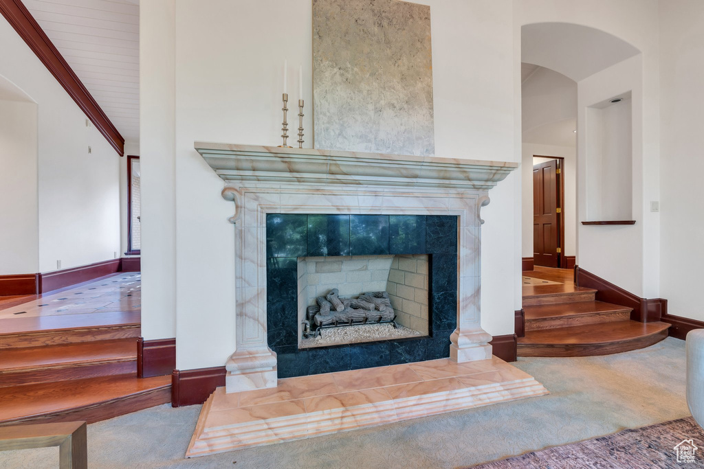 Detailed view of a tiled fireplace, carpet flooring, arched walkways, and baseboards