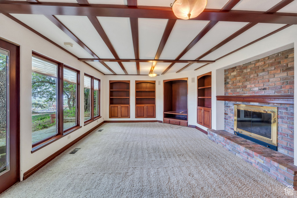 Unfurnished living room with built in features, a fireplace, and carpet floors