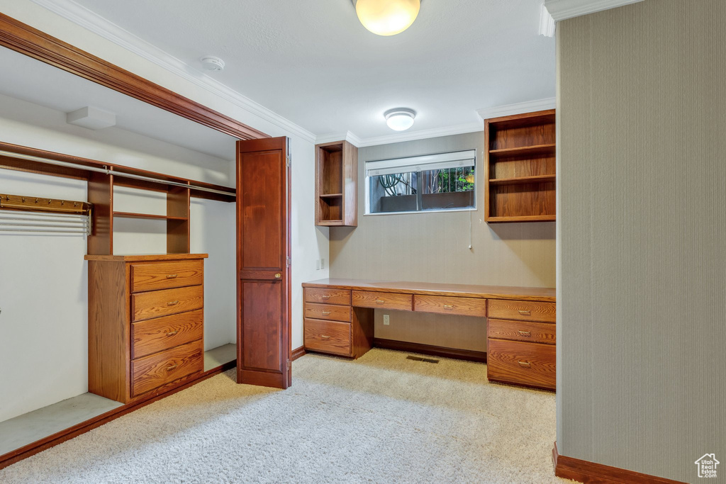 Walk in closet with built in desk and light carpet
