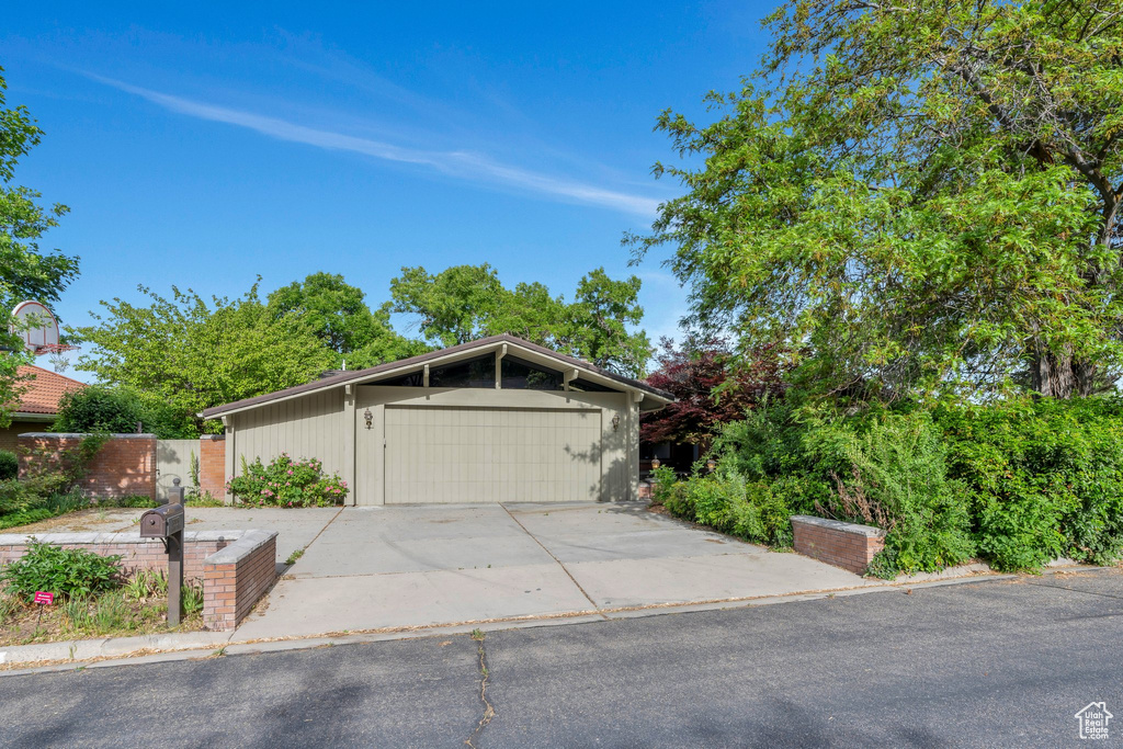 View of front of property with fence, driveway, and a garage