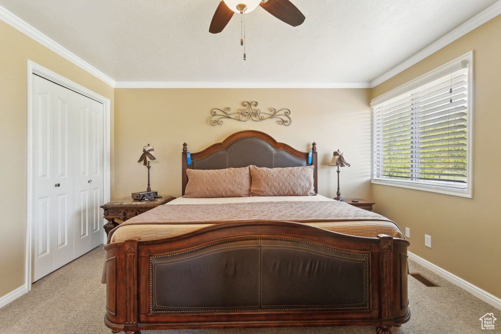 Bedroom featuring light colored carpet, ornamental molding, a closet, baseboards, and a ceiling fan