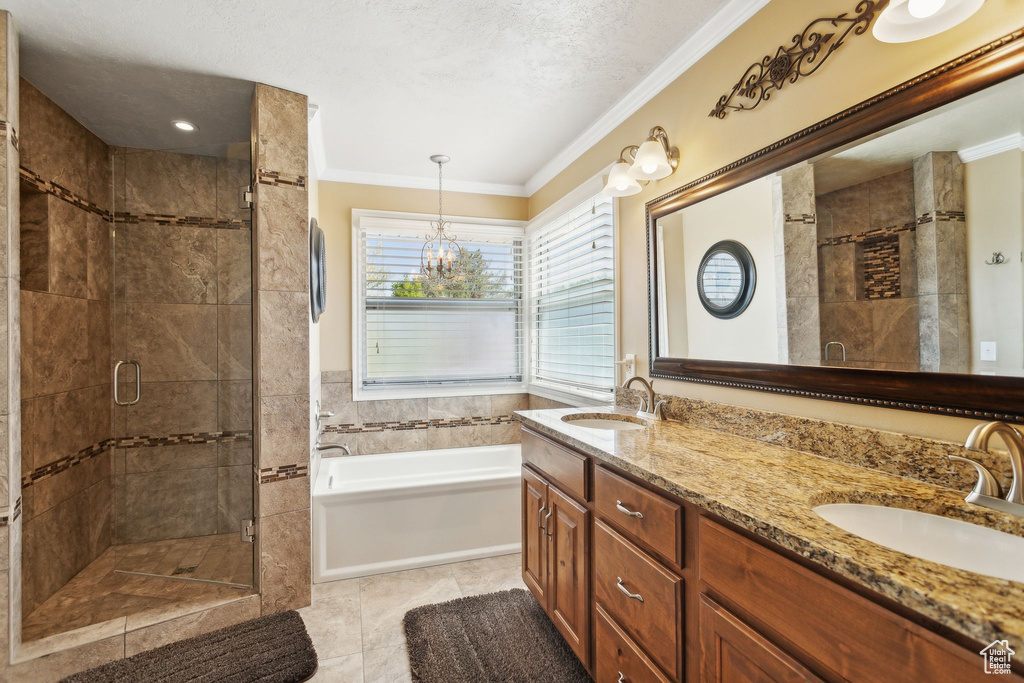 Full bathroom featuring a stall shower, crown molding, a garden tub, double vanity, and a chandelier