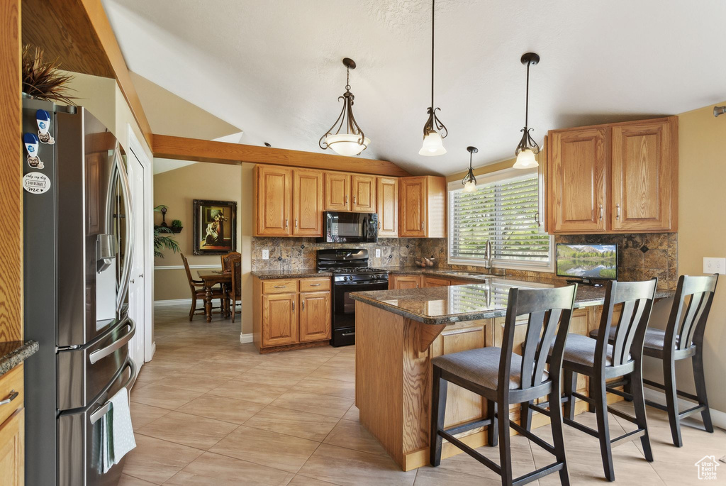 Kitchen with black appliances, decorative backsplash, a peninsula, a kitchen bar, and lofted ceiling
