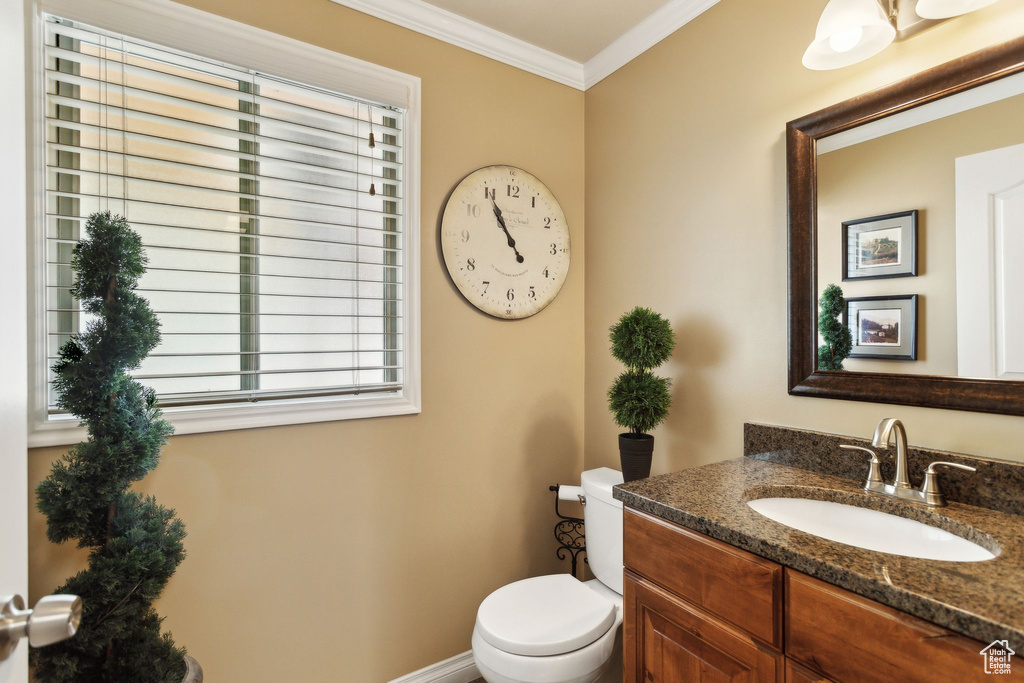 Bathroom featuring crown molding, toilet, vanity, and plenty of natural light