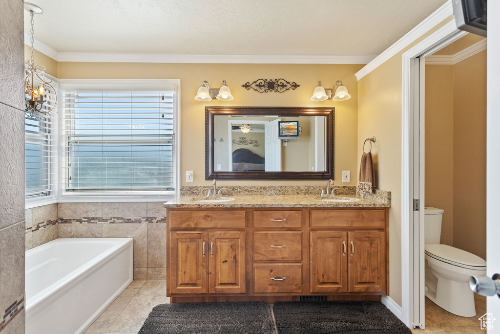 Full bath with a chandelier, double vanity, toilet, tile patterned floors, and a garden tub