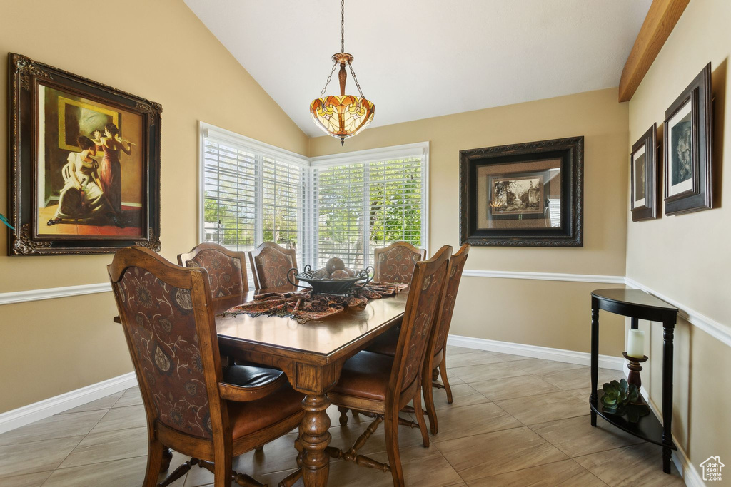 Tiled dining area with lofted ceiling and baseboards