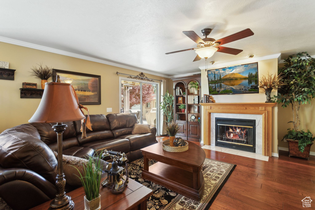 Living area with ceiling fan, wood finished floors, crown molding, a fireplace with flush hearth, and baseboards