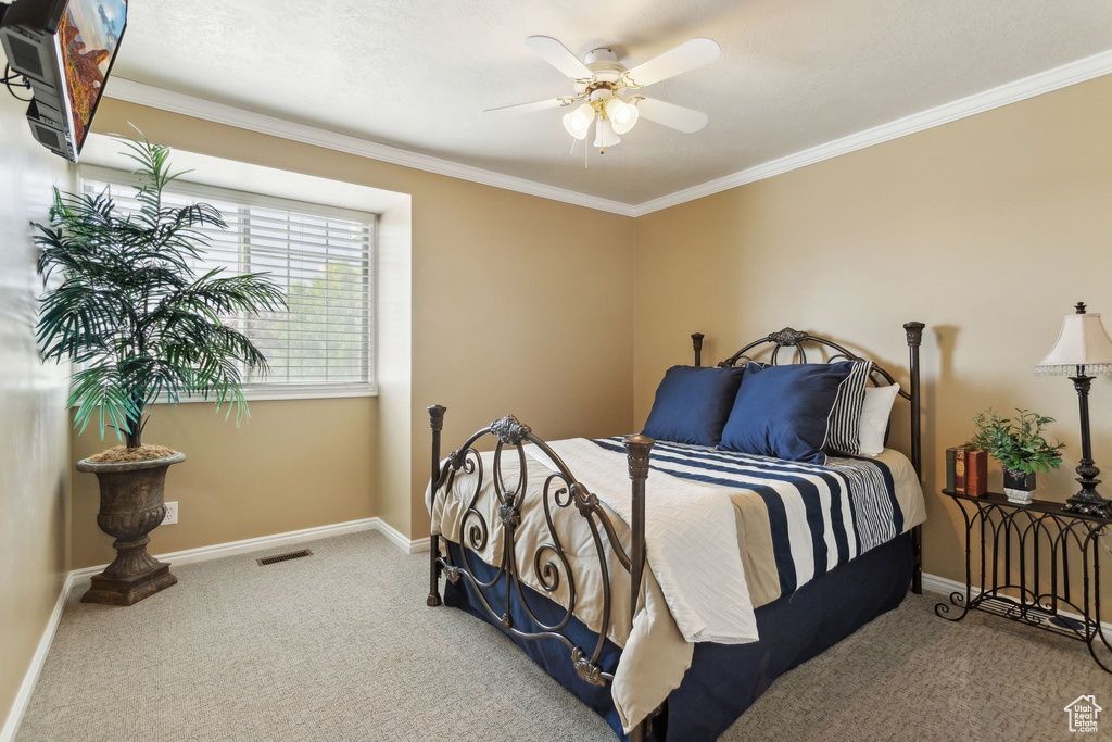 Carpeted bedroom featuring ornamental molding, baseboards, and a ceiling fan