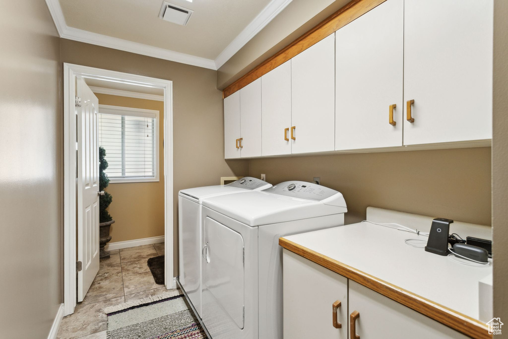 Clothes washing area with cabinet space, independent washer and dryer, crown molding, and baseboards