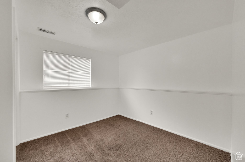 Unfurnished room with dark carpet and baseboards
