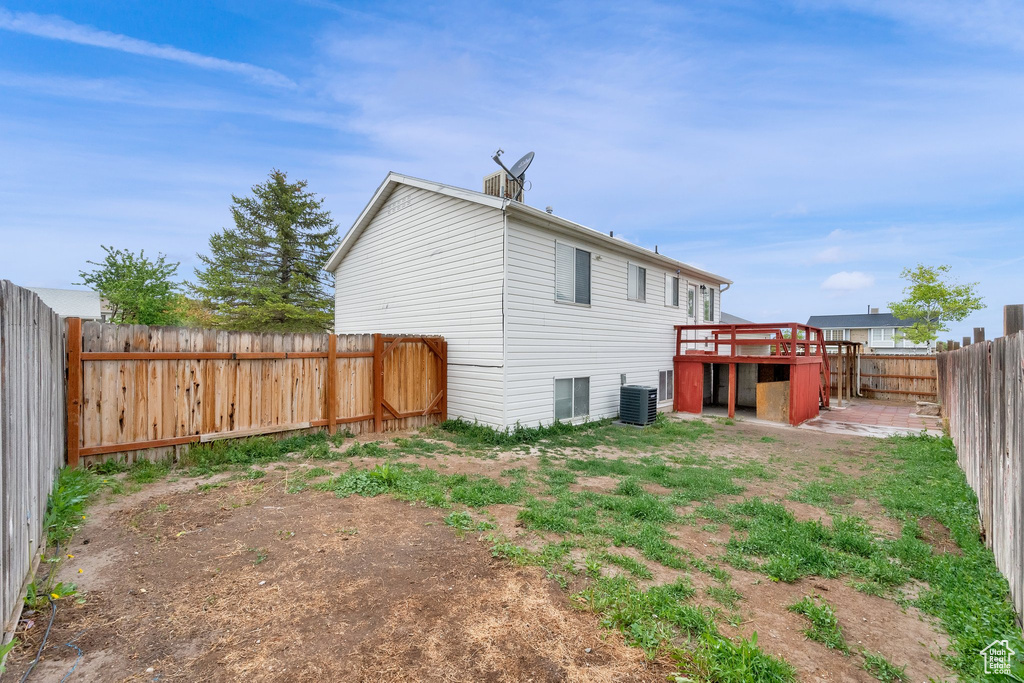 Back of property with central AC, a fenced backyard, and a deck